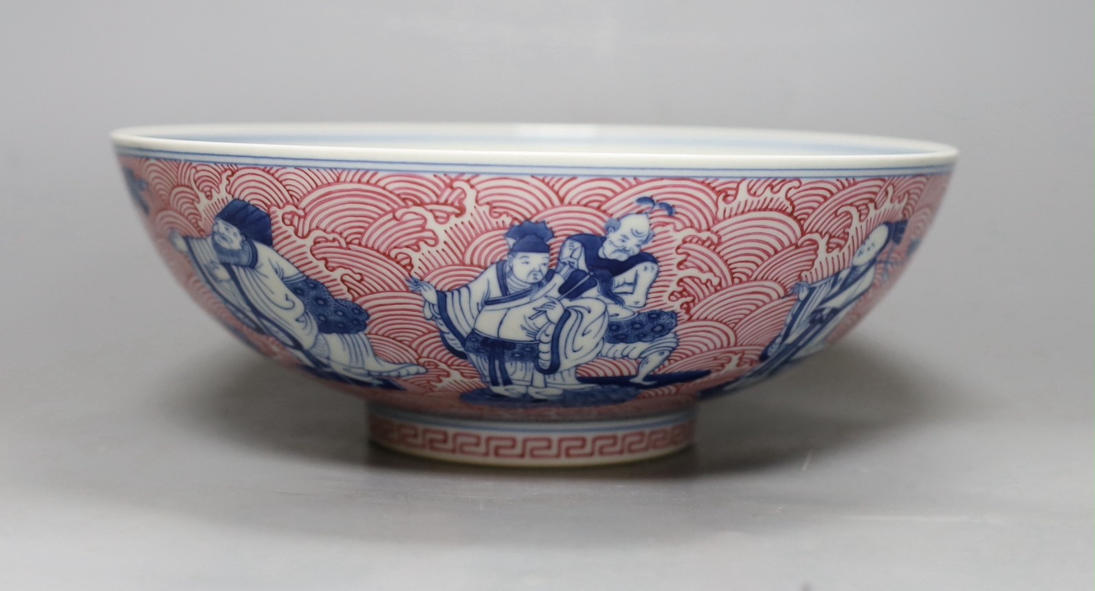 A Chinese underglaze blue and puce enamelled 'eight immortals' bowl, 22cm diameter